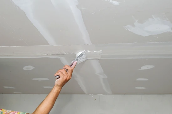 Les ouvriers du b&acirc;timent placent des panneaux de pl&acirc;tre ou de pl&acirc;tre sur le mur avec la truelle