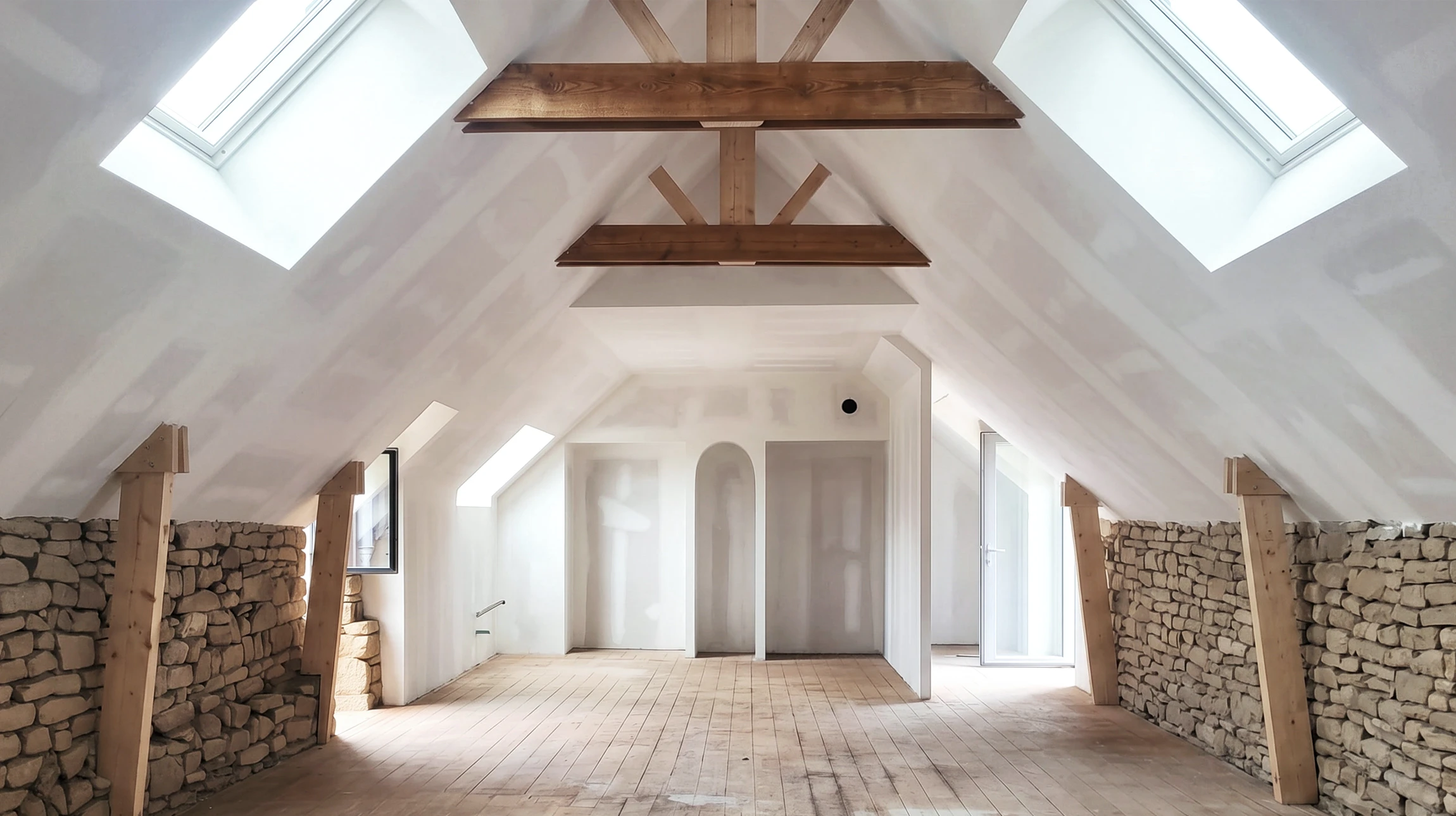 Grenier en cours de r&eacute;novation, vaste espace sous combles avec plancher en bois brut, mur en pierre apparente, cloisons en placo joints non finis
