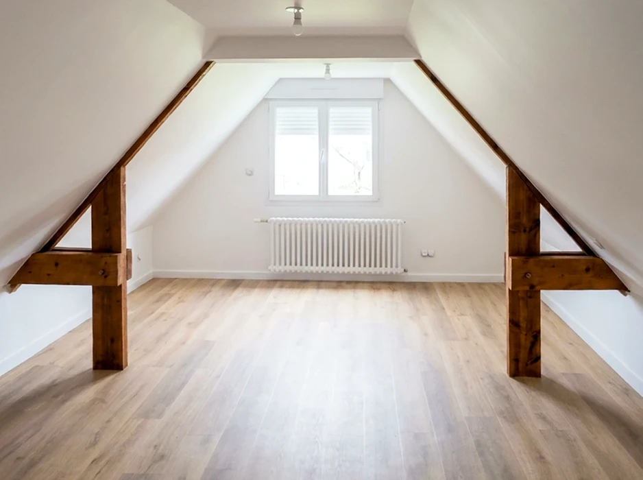 Chantier de construction résidentielle en cours, combles aménageables avec charpente bois apparente et isolation thermique jaune entre chevrons