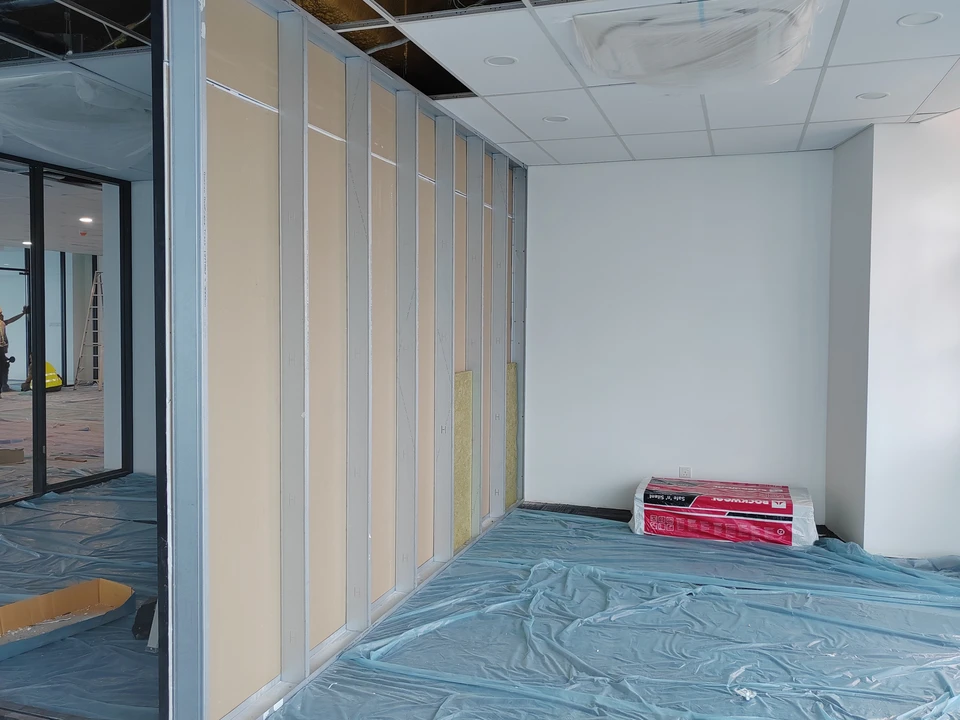 Ouvrier en bâtiment installant des cloisons sèches dans un intérieur en rénovation