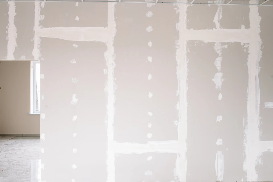 Ouvrier en salopette appliquant de l'enduit au plafond dans une pi&egrave;ce en r&eacute;novation